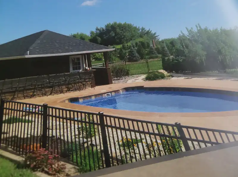 Black aluminum pool safety fence with self-closing gate around a swimming pool